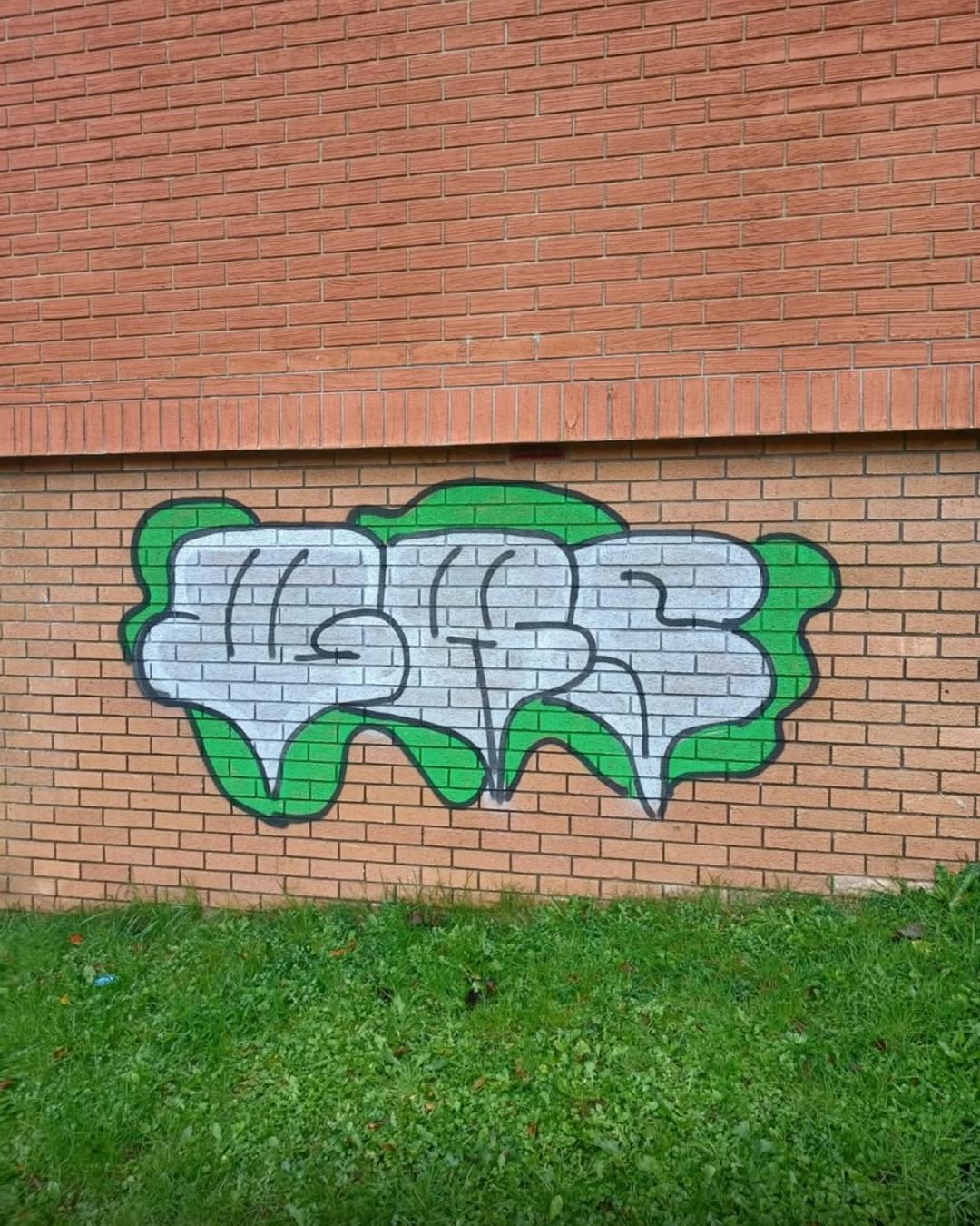 Green graffiti on brick wall